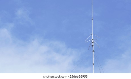 Una vieja antena de radio amateur de pie contra un fondo de cielo y nubes.