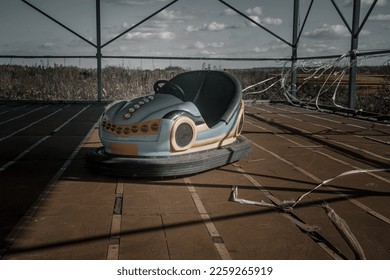 An old amusement ride in an abandoned amusement park. Abandoned carousel and cars. Sunny day. Old abandoned amusement park.