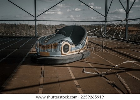 An old amusement ride in an abandoned amusement park. Abandoned carousel and cars. Sunny day. Old abandoned amusement park.