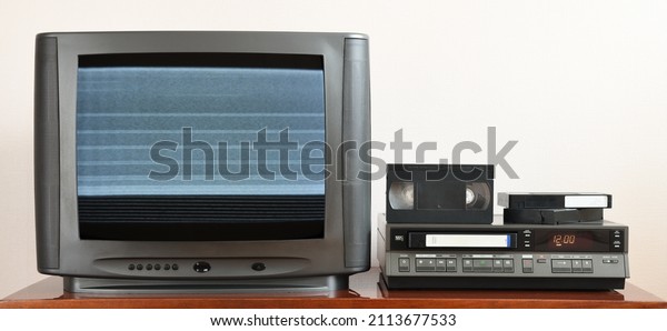 Old analog TV with noise on the
screen and VCR. Old black TV with VCR on wallpaper background.
