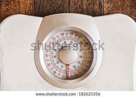Old analog weight scale isolated on wooden floor