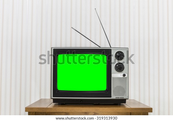 Old analogue television on wood table with chroma\
key green screen.