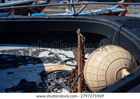Old anchor with rusted chain and delicate spider webs aboard a wooden fishing boat. Authentic maritime detail captured during low tide on a tropical shoreline.