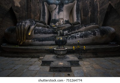 Old Ancient Buddha Statue With Yellow Candle And Joss Stick In Burner Pot