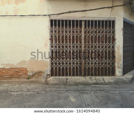 Old and ancient iron door with rust. The cement wall with cracks, decay, saw the red brick structure.