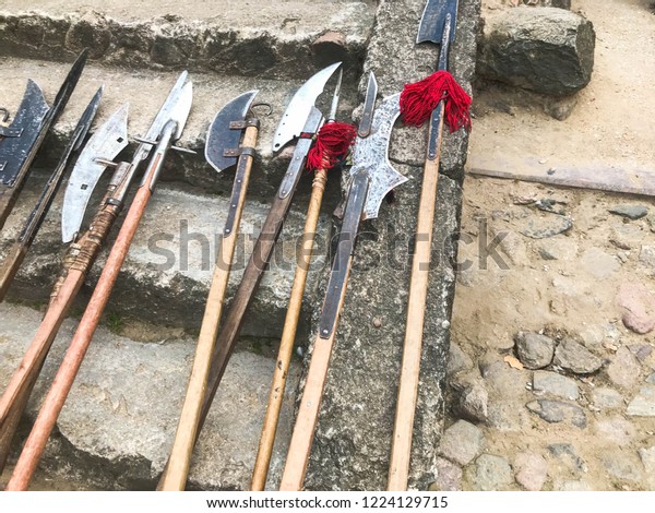 The old ancient medieval cold weapons, axes,\
halberds, knives, swords with wooden handles lick on the stone\
steps of the castle.