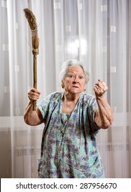 Old angry woman threatening with a broom at home