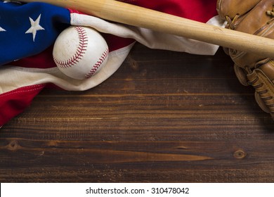 An Old, Antique American Flag With Vintage Baseball Equipment On A Wooden Bench