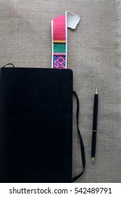 An Old Antique Black Diary, Book, Poetry Book, A Colorful Vintage, Retro Book Mark And A Black Writing Pen;