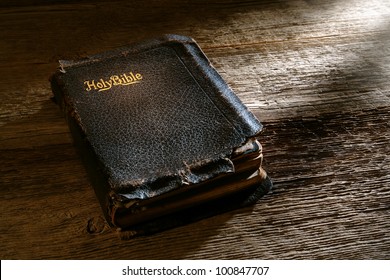 Old antique and damaged holy bible sacred religious book on weathered wood bench in a vintage church