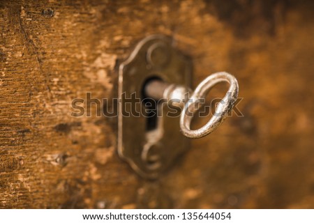 Old antique skeleton key in lock of wooden cabinet