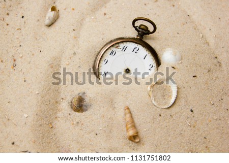 Old and antique vintage clock pocket watch in the sand of a beach without pointers, symbolizes the concept of no time or timeless, no rush, end of time or everlasting and forever, deadline 