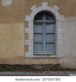 An old arched window in a wall with stone accents and light fixtures