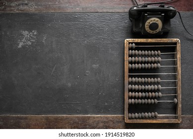 Old arithmetic abacus and black rotary phone on the desk top view background with copy space.