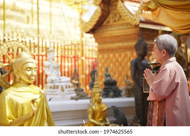 old asian elder senior woman traveler tourist praying at buddhist temple.