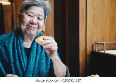 Old Asian Elderly Senior Elder Woman Eating Bread At Restaurant. Mature Retirement Lifestyle