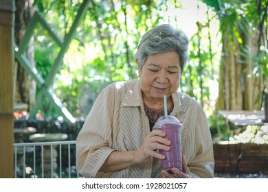 Old Asian Elderly Senior Elder Woman Drinking Berry Smoothie Yogurt Milkshake At Restaurant. Mature Retirement Lifestyle