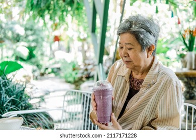 Old Asian Elderly Senior Elder Woman Drinking Berry Smoothie Yogurt Milkshake At Restaurant. Mature Retirement Lifestyle