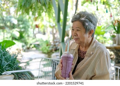 Old Asian Elderly Senior Elder Woman Drinking Berry Smoothie Yogurt Milkshake At Restaurant. Mature Retirement Lifestyle