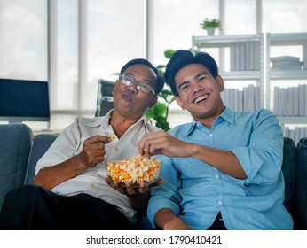 Old  Asian Father Was Spending Joyful Time With Mature Adult Son At Home  On Couch.  Enjoying Technology Lifestyle Concept.  Social Distancing New Normal Concept. 