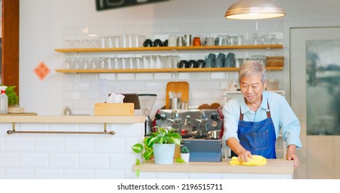 Old Asian Man Cleaning The Counter In A Coffee Shop 