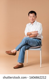 An old asian man sitting on grey chair and smiling in studio beige background.
 - Shutterstock ID 1606862212