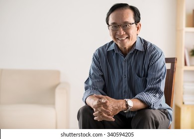 Old Asian Man Sitting On Chair And Smiling At Camera