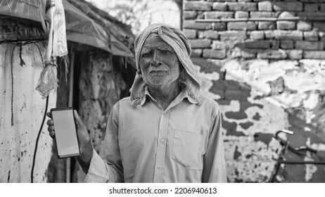 Old Asian Man Smiling And Showing A Green Screen Cell Phone With Rural Village Life Concept Background.