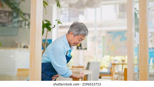 Old Asian Man Wecomimg Customers At Front Door In Cafe Or Restaurant