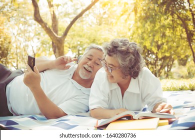Old asian people, senior couple, elderly man and elderly woman get picnic in park. Old husband listening music, lay down on old wife back. Grandma look at husband. Senior couple enjoy life, happiness - Powered by Shutterstock