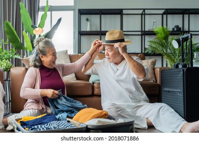 old asian senior couple packing cloth and stuff for a trip together,happiness asian old age retired mature adult enjoy arrange cloth together on floor at living room at home interior background
