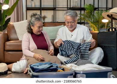 Old Asian Senior Couple Packing Cloth And Stuff For A Trip Together,happiness Asian Old Age Retired Mature Adult Enjoy Arrange Cloth Together On Floor At Living Room At Home Interior Background