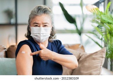 old asian senior female wearing face mask virus protection happiness cheerful show bandage injection covid-19 vaccinated with hand gesture point and confident for virus protection  - Powered by Shutterstock