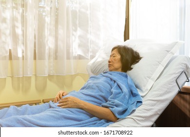 An Old Asian Woman Lying On The Bed Besides The Windows To Rest And Recover Because Of Flu