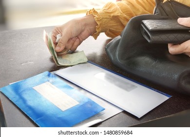 Old Asian Woman Is Paying For Car Inspection Service Fee And Insurance Policy For Further License Plate Renewal At Vehicle Inspection Service Center Over Weekend. Selective Focus On Hand & Cash