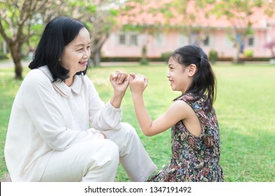 old asian woman use pinky finger holding  
 pinky finger of asian children, they feeling happy in family time, retirement happiness, mother day