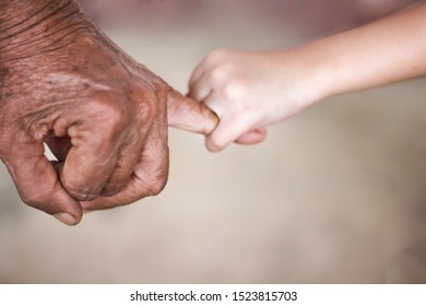 Old asian woman with wrinkles hand and girl child making a pinkie promise