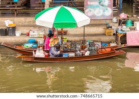 Old asians woman making thai noodle food at Damnoen Saduak floating market in Ratchaburi near Bangkok, Thailand