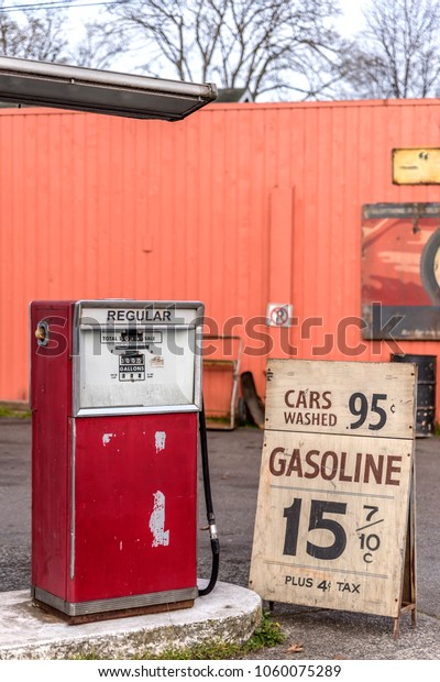 old auto gas station,\
advertising for cheap gasoline, rusty metal barrels, on a summer\
day