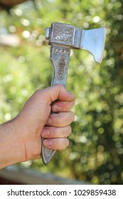 Old Ax In Hand Over Green Background