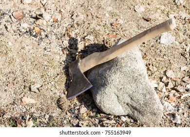 old axe on the ground in the rays of the sun