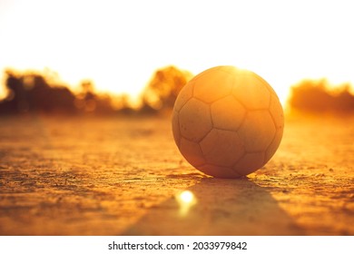 An Old Ball For Street Soccer Football Under The Sunset Ray Light. Concept For Sport And Exercise For Kids.Picture With Copy Space.