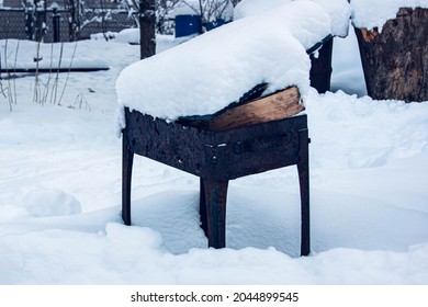Old barbecue covered with snow. It is packed with firewood, which means you can start cooking something delicious. Winter will not be hungry. The stylized treatment of the mood.