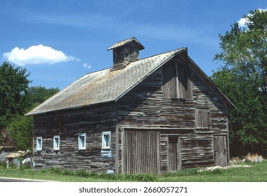 An old barn characterized by rustic wooden architecture, showcasing its weathered charm and the beauty of agricultural history in a pastoral setting.