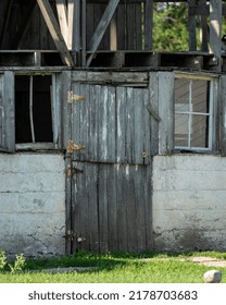 Old Barn That Is Falling Apart With Faded Barn Doors Barely Hanging On To The Wall