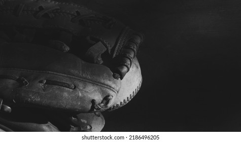 Old Baseball Glove With Ball On Dark Background In Black And White.