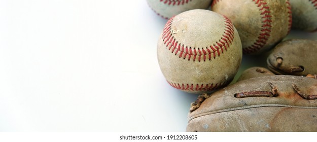 Old baseballs with glove isolated on white background beside sports game equipment.