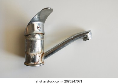 Old Bathroom Sink Faucet contaminated with calcium, grime and rust. Hard water stain build-up. Awful condition of the water pipe. A layer of rust is visible inside. Dangerous for health