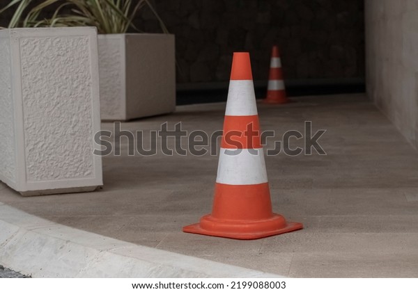 an old battered\
orange road cone stands on the road enclosing a parking place\
within the city limits. Road regulation tools that have\
deteriorated from\
exploitation.