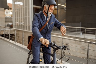 Old bearded manager in helmet checking time over wristwatch while riding bicycle to work on city street - Powered by Shutterstock